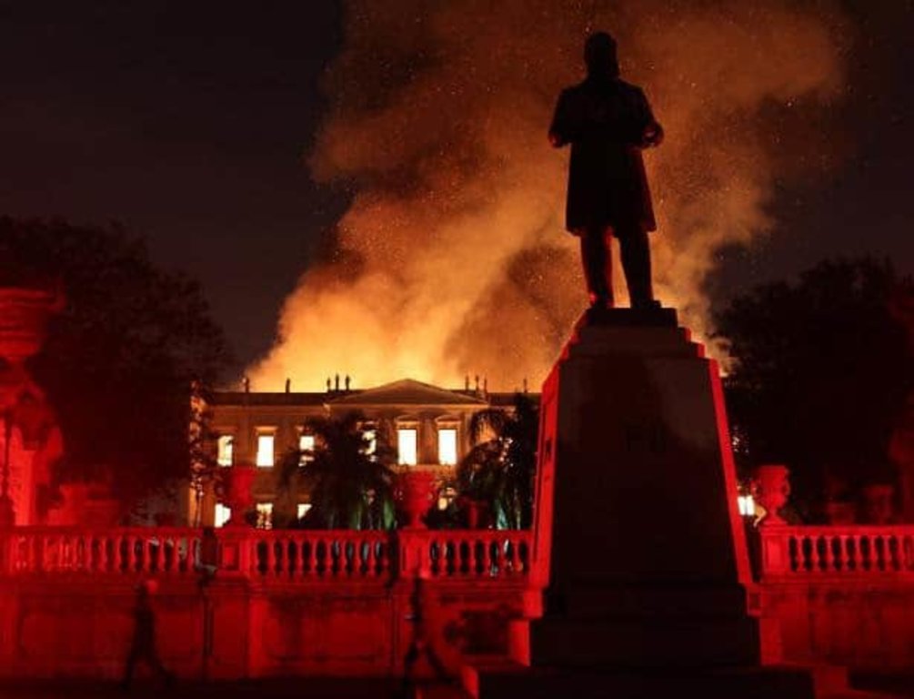 Nosso passado virou cinzas. A silhueta da estátua de D. Pedro II assiste impotente o fogo acabar com 200 anos de história (Foto Marcelo Moraes /Reuters) - Gente de Opinião